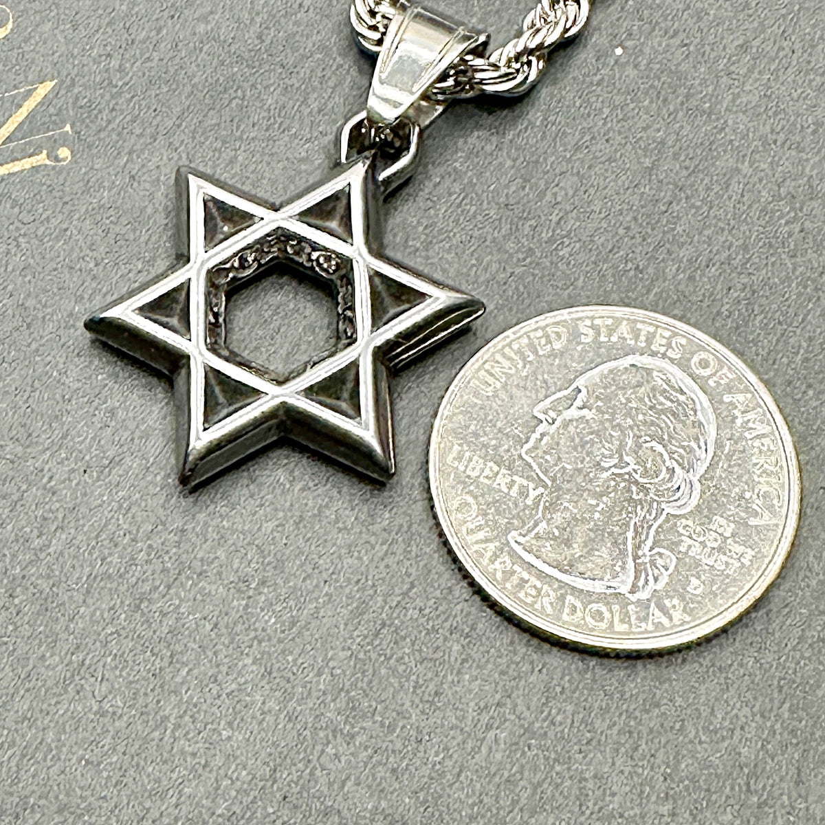 Blackened Star of David pendant beside a US quarter for size, about 26mm across