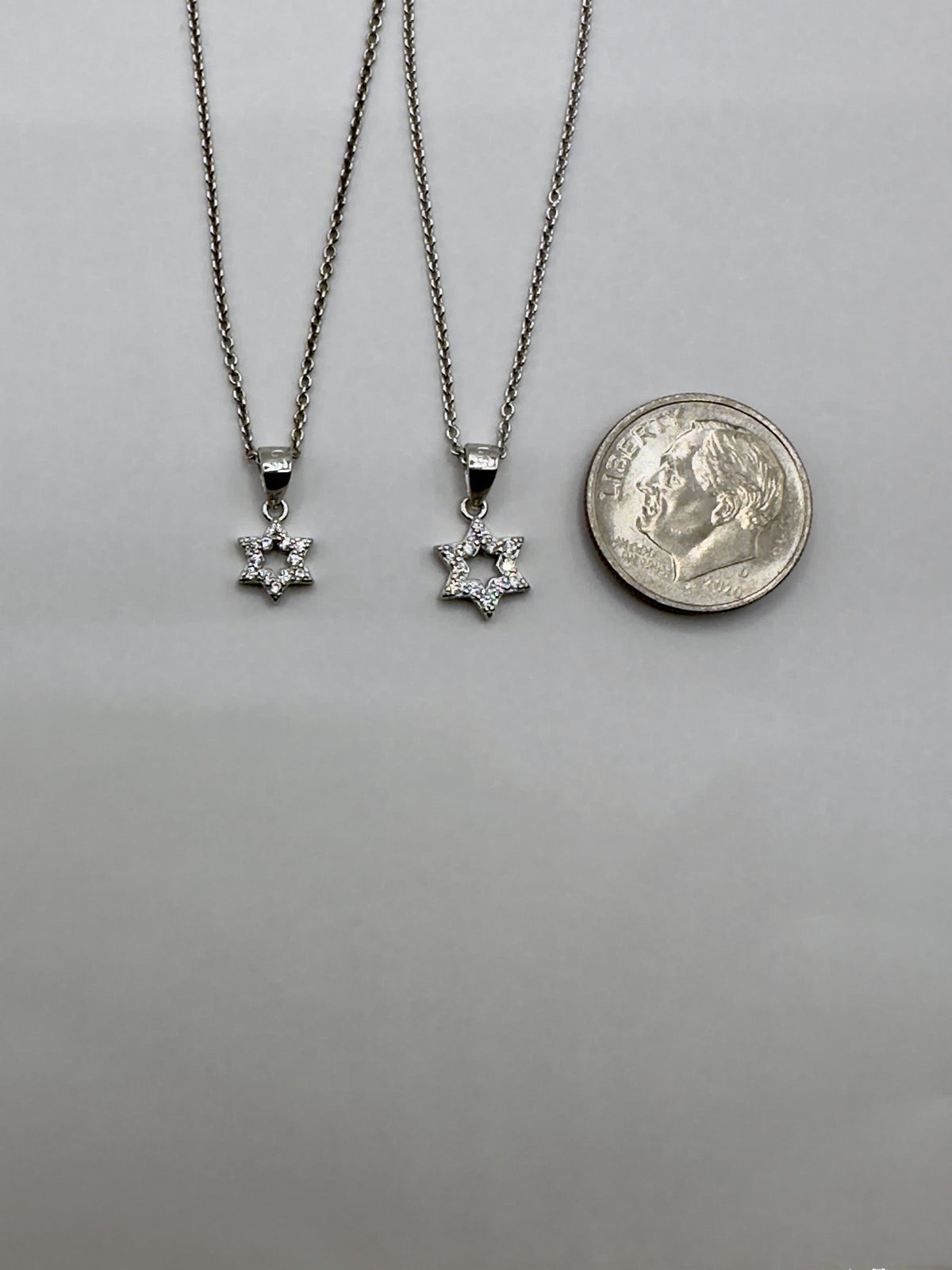 Both Star of David pendant sizes beside a dime, 6mm and 7.5mm across