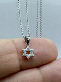 Dainty pavé Star of David pendant on a fingertip for scale