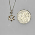Petite sterling silver Star of David pendant next to a dime for scale