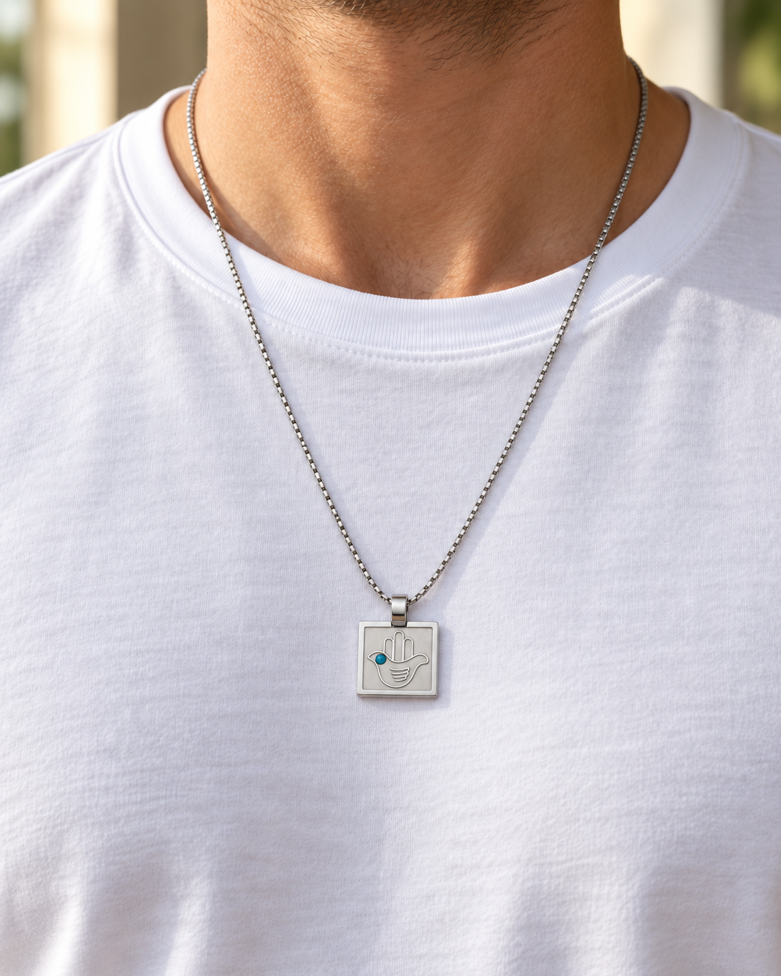 Silver dove hamsa pendant necklace worn over a white t-shirt